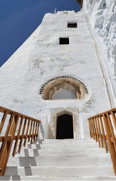 A whitewashed tower with a carved doorway and wooden stairs
