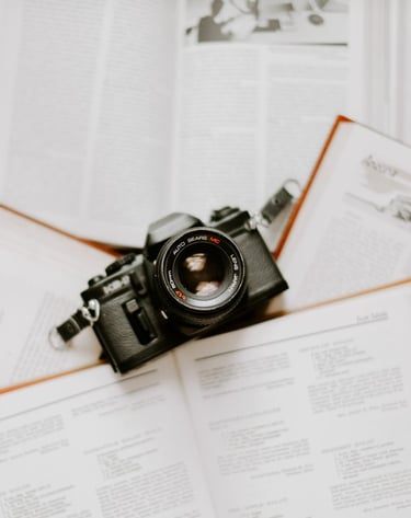 A vintage film camera resting on open books