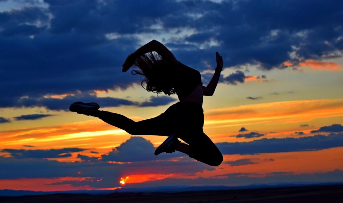 A dancer leaping against a vivid sunset sky