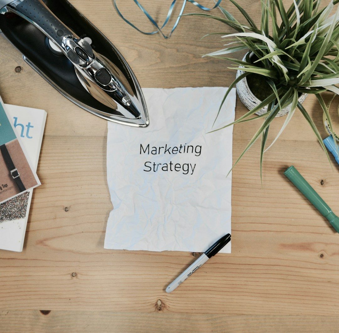A sheet of paper reading Marketing Strategy on a workbench with markers, brochures and a plant