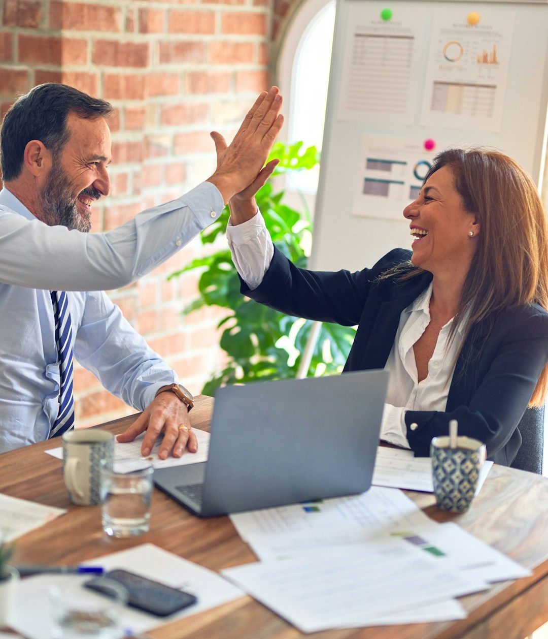 Two professionals celebrating a deal at a meeting