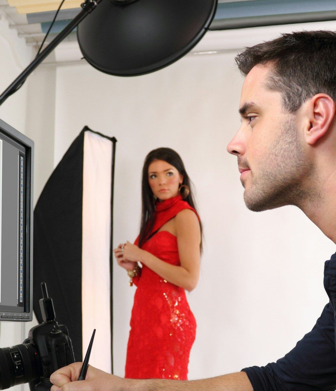 A photographer shooting a model in a red dress in a studio