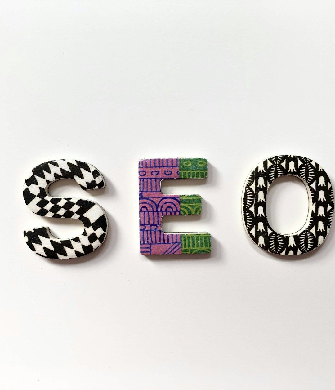 The letters S E O in patterned wooden type